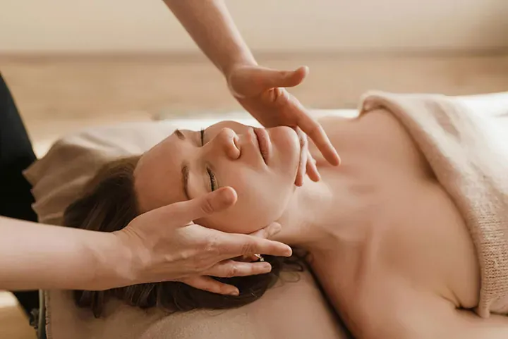 Osmosis facial infusion Client with eyes closed receiving a relaxing facial infusion, esthetician's hands cradling her jaw